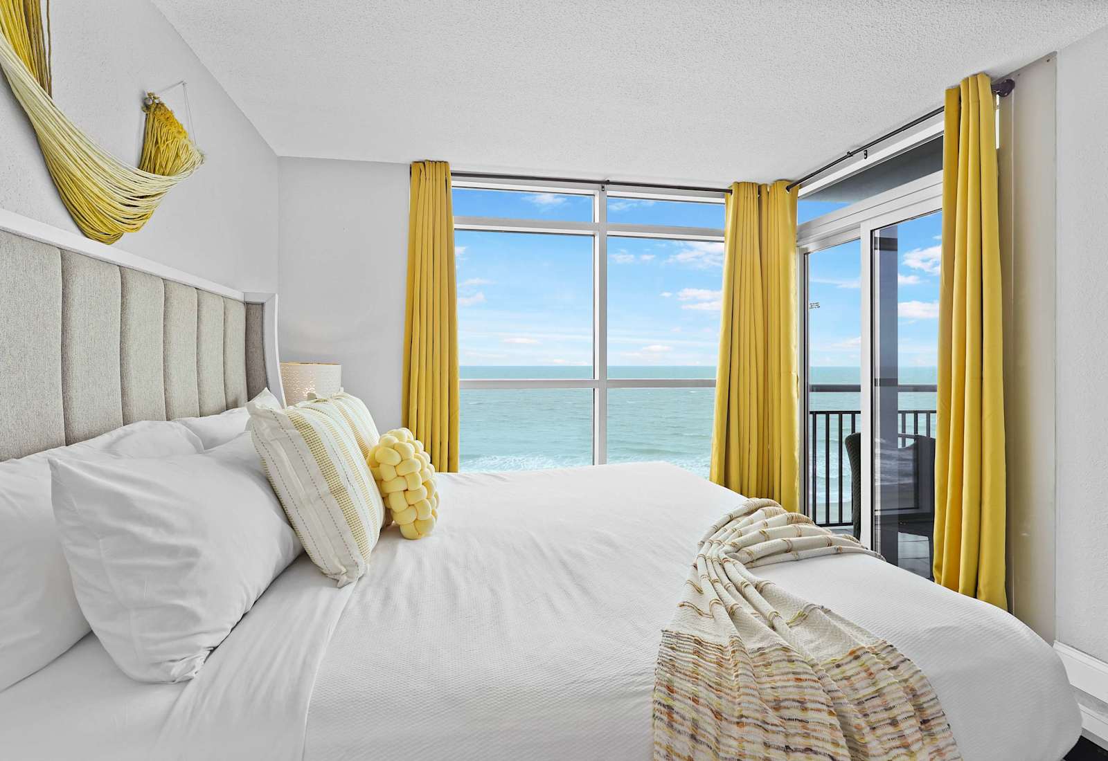 Wake up to breathtaking oceanfront views in this bright and cheerful bedroom! Featuring a plush bed, sunny yellow accents, and floor-to-ceiling windows—your dreamy Myrtle Beach escape begins right here.