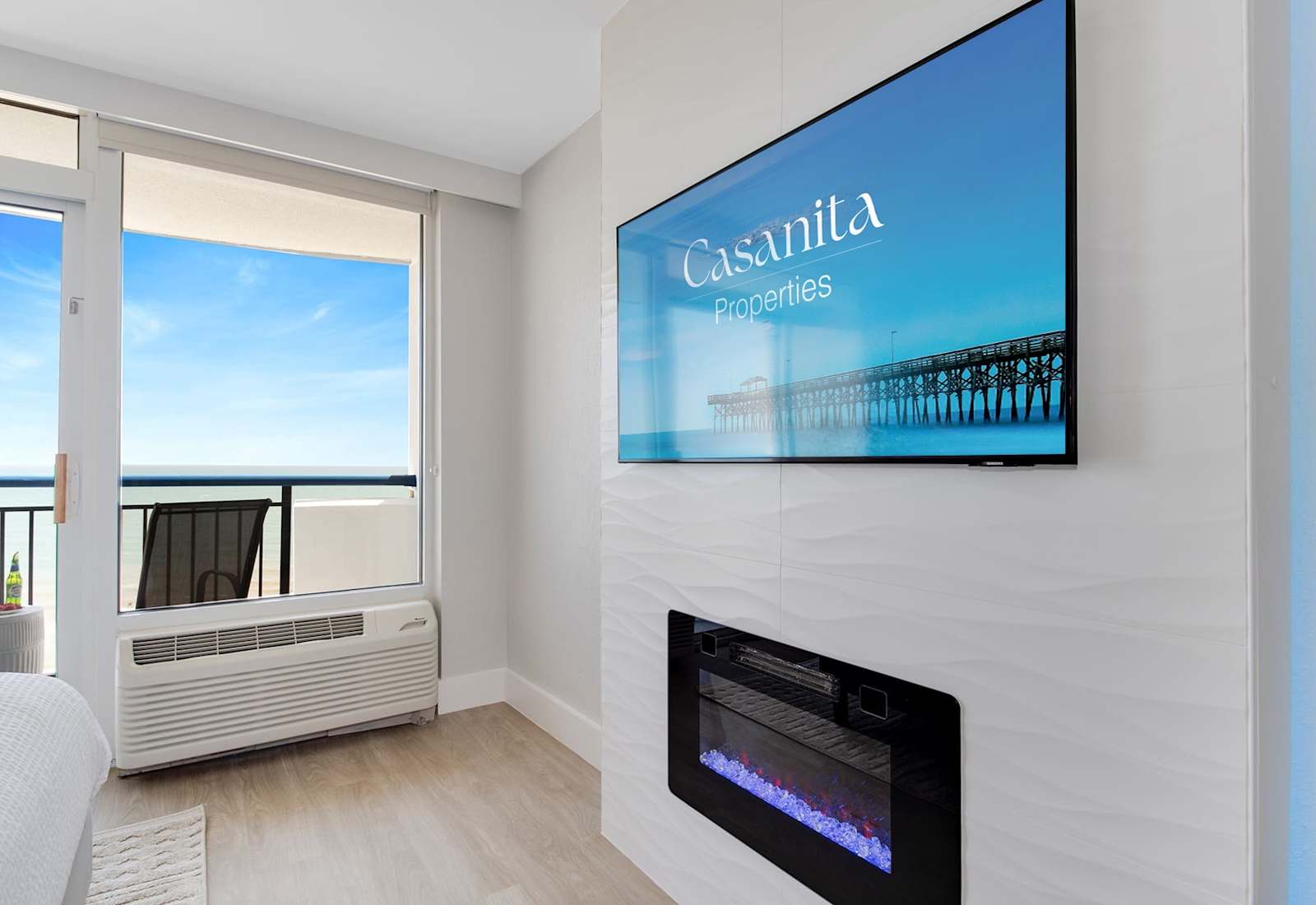  This cozy corner features a sleek TV and a stylish electric fireplace, perfect for unwinding. Step out onto the balcony to feel the sea breeze or relax inside while enjoying scenic views and soothing ambiance.