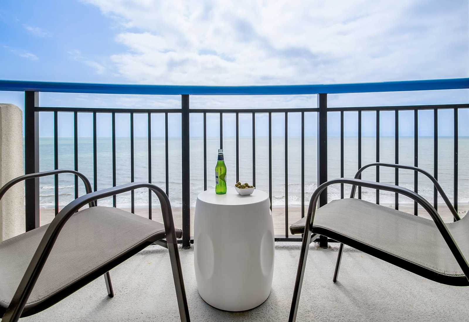 Step out onto your private balcony and soak in panoramic ocean views. With comfortable seating and a side table perfect for snacks or drinks, this serene spot invites you to unwind and enjoy the gentle sea breeze and the calming sound of the waves.