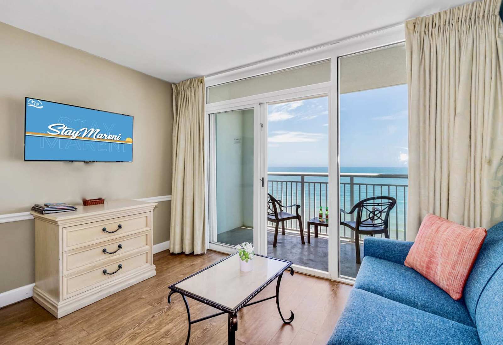 Unwind in this cozy living space with direct access to a private balcony showcasing panoramic ocean views. Relax on the plush sofa, catch your favorite shows, and sip drinks as the sea breeze flows in. Perfect for a tranquil beach escape!