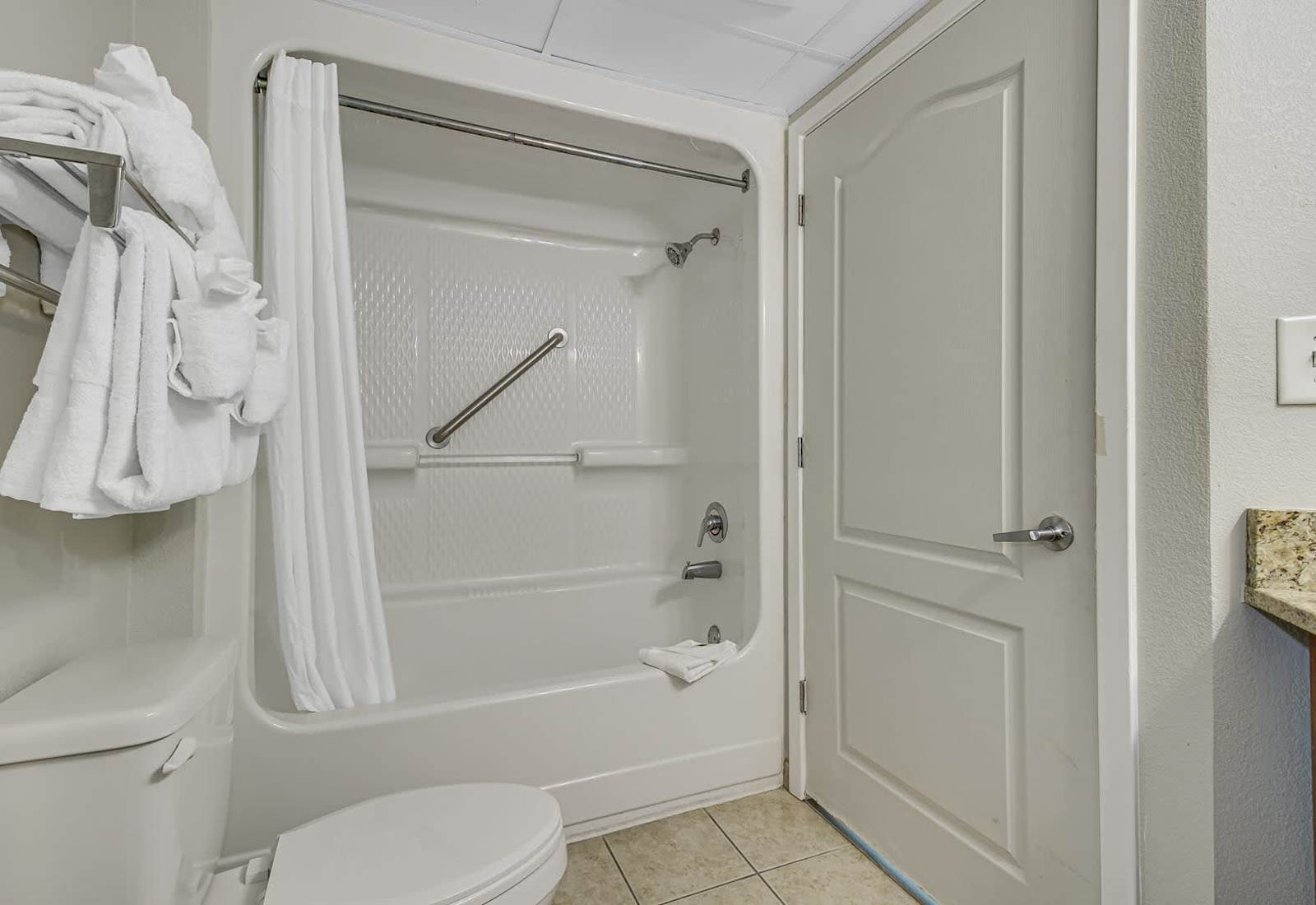 Practical full bathroom with a shower-tub combo, fresh towels, and simple essentials for an easy, comfortable stay.