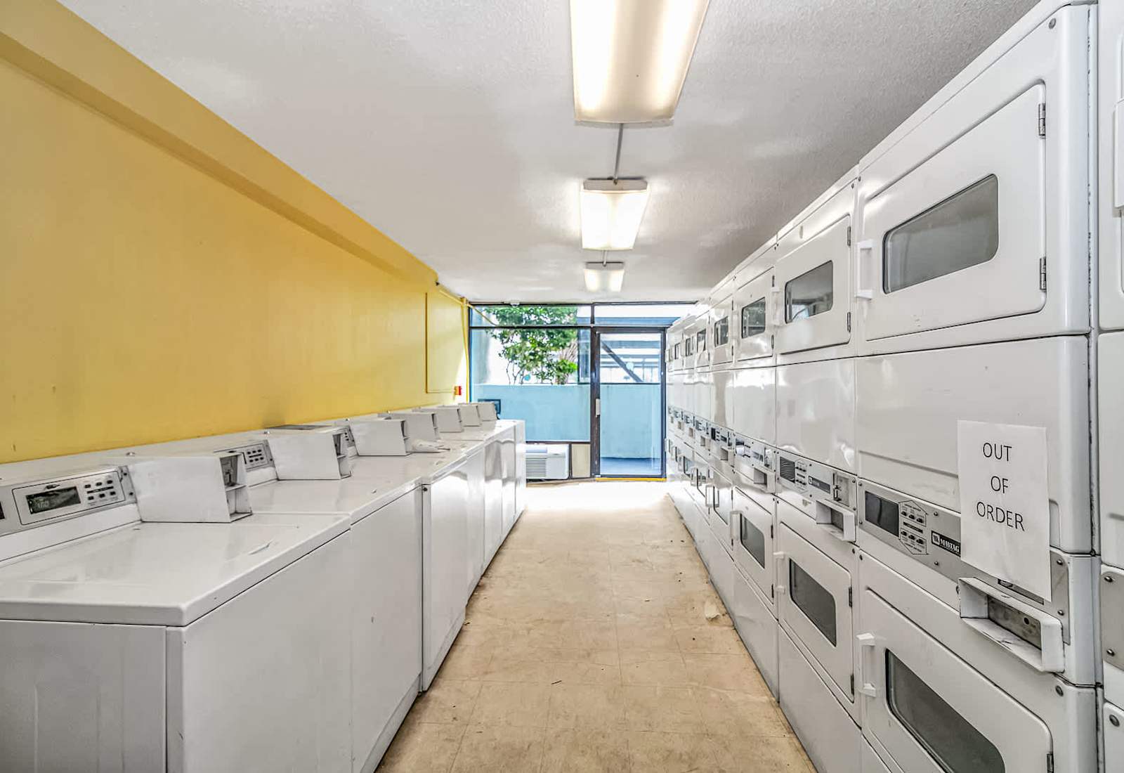 Resort laundry facility featuring rows of coin-operated top-loading washing machines and stacked dryers.