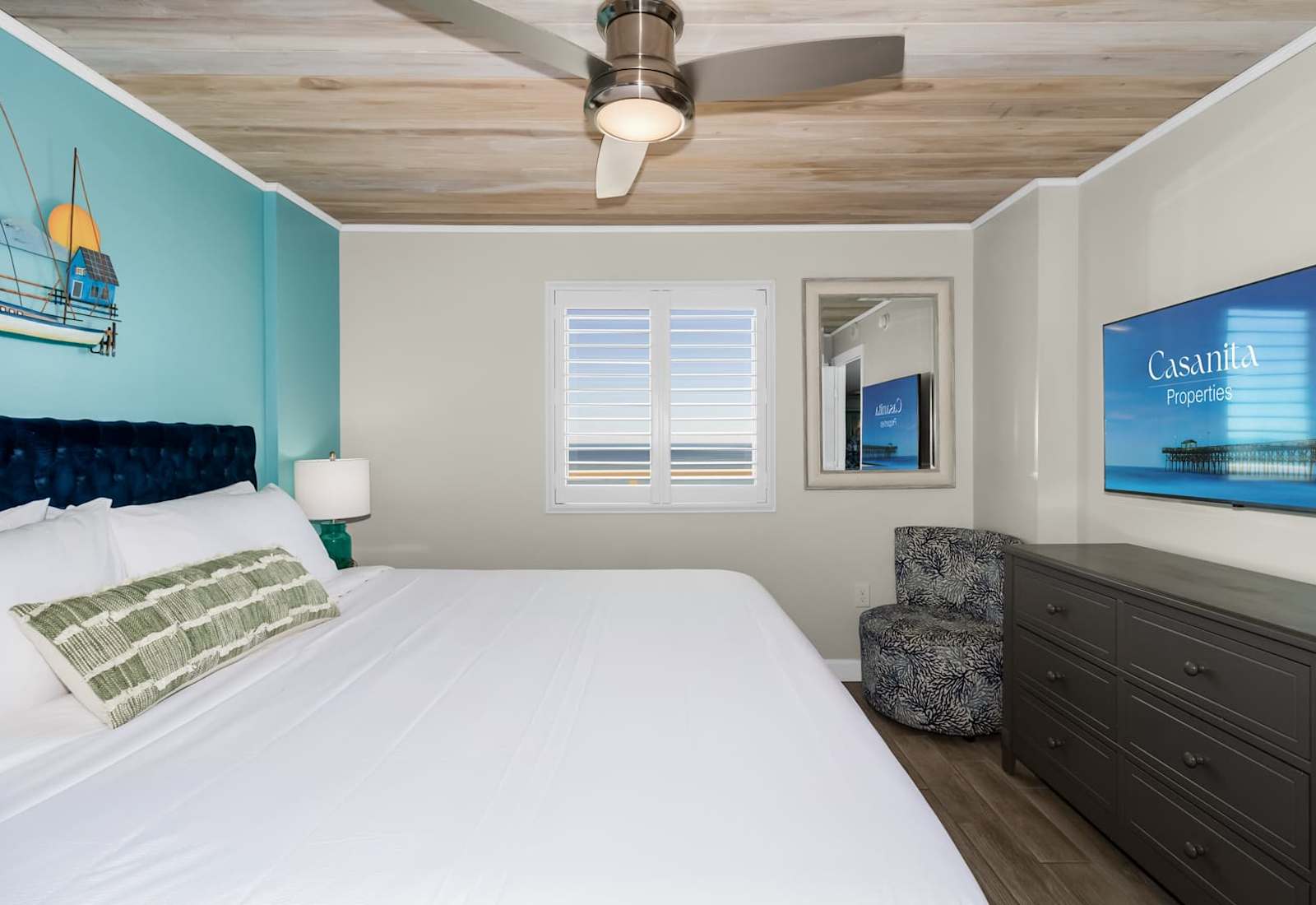 Retreat to this serene bedroom featuring a plush bed, stylish decor, and a flat-screen TV for entertainment. Wake up to natural light and glimpses of the ocean, creating a perfect blend of comfort and coastal charm.