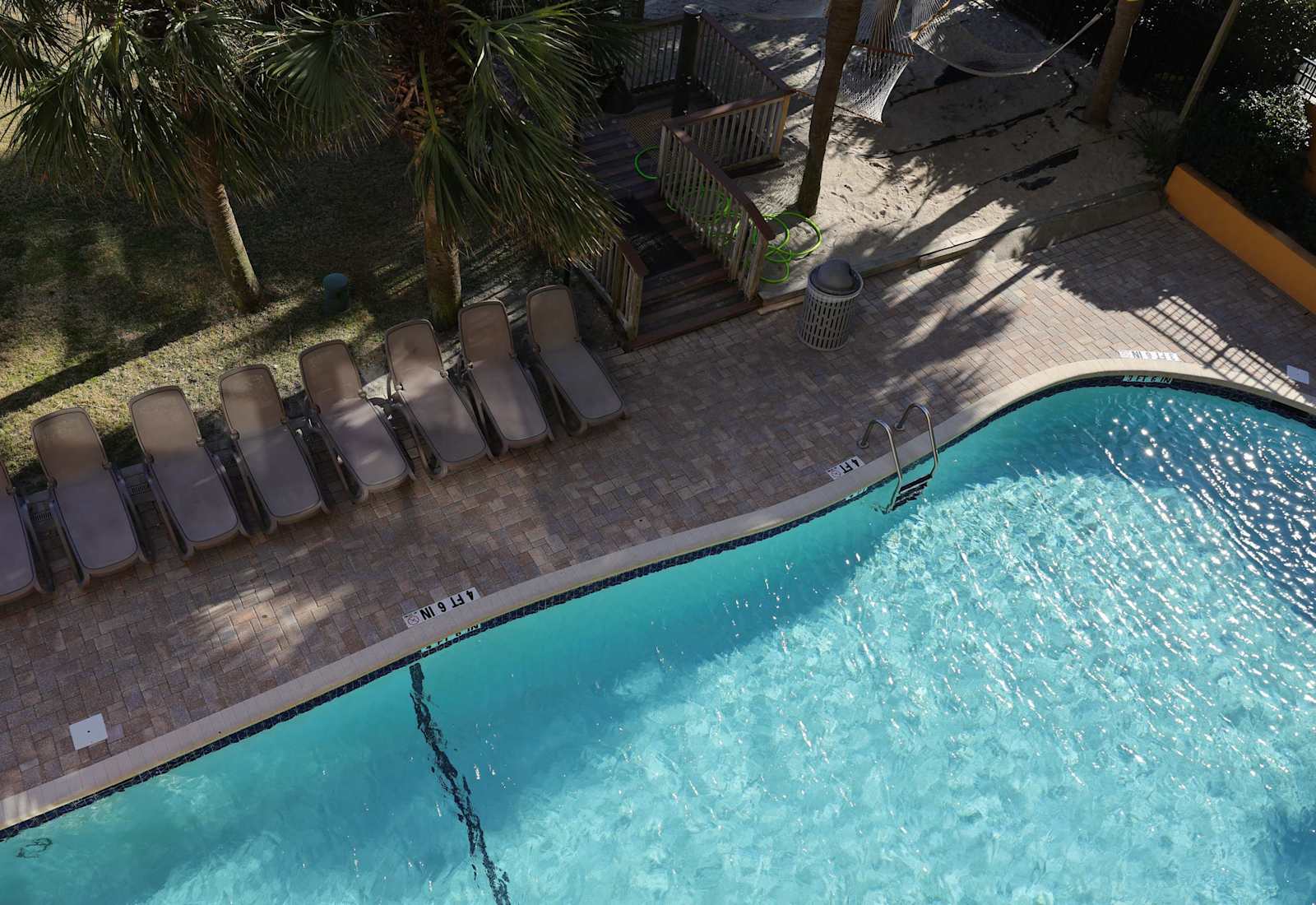Enjoy access to the outdoor pool area, complete with lounge chairs, palm trees, and a relaxing coastal atmosphere just steps from the beach.
