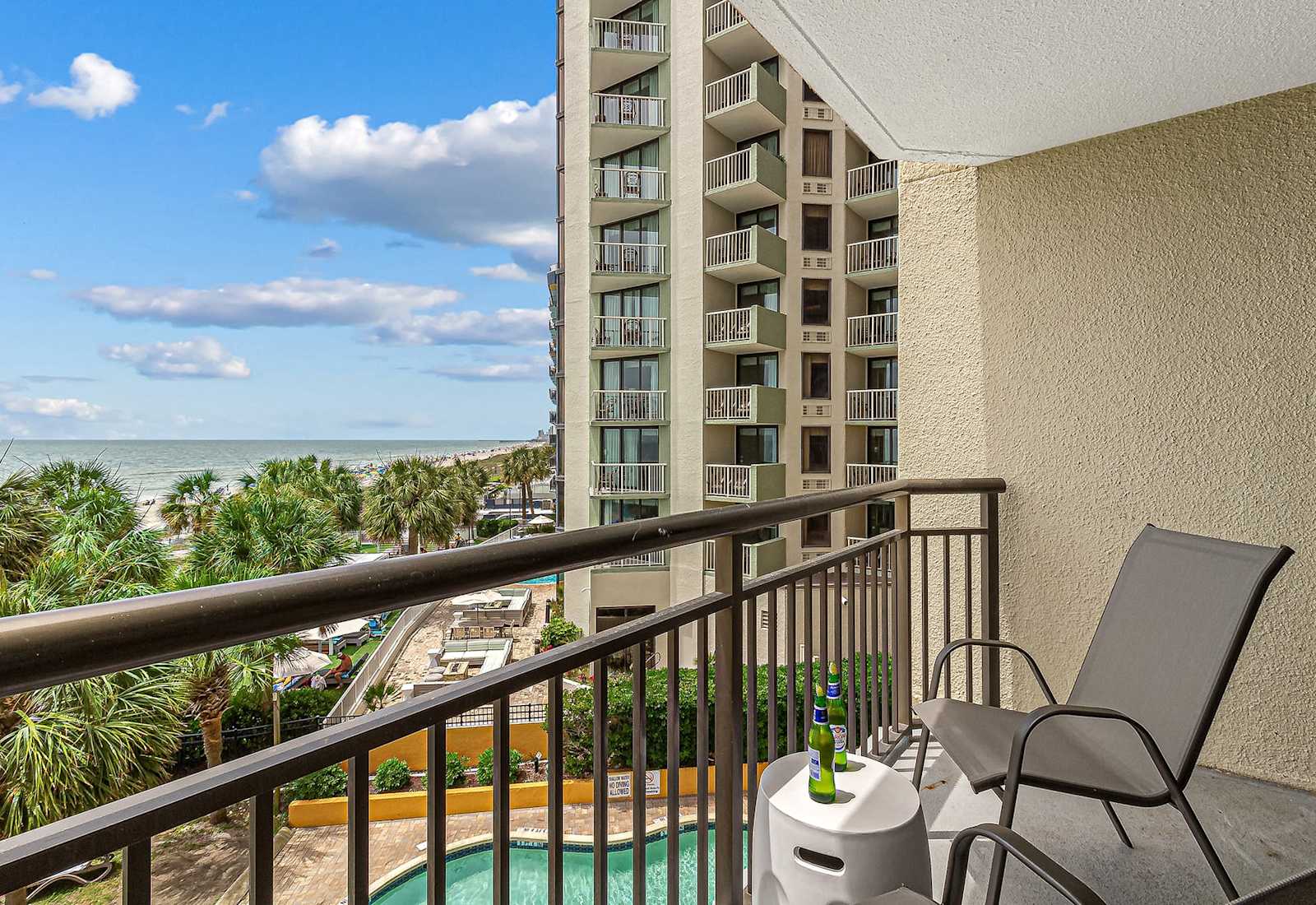 This private balcony invites you to enjoy ocean breezes, palm tree views, and the lively beach scene below. A peaceful retreat just steps from the sand and surf.