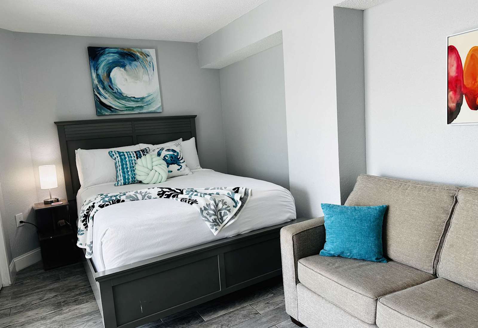 Relax and recharge in this cozy, coastal-inspired bedroom featuring a plush bed, comfy seating, and vibrant artwork. The perfect spot to unwind after a fun-filled day exploring Myrtle Beach!