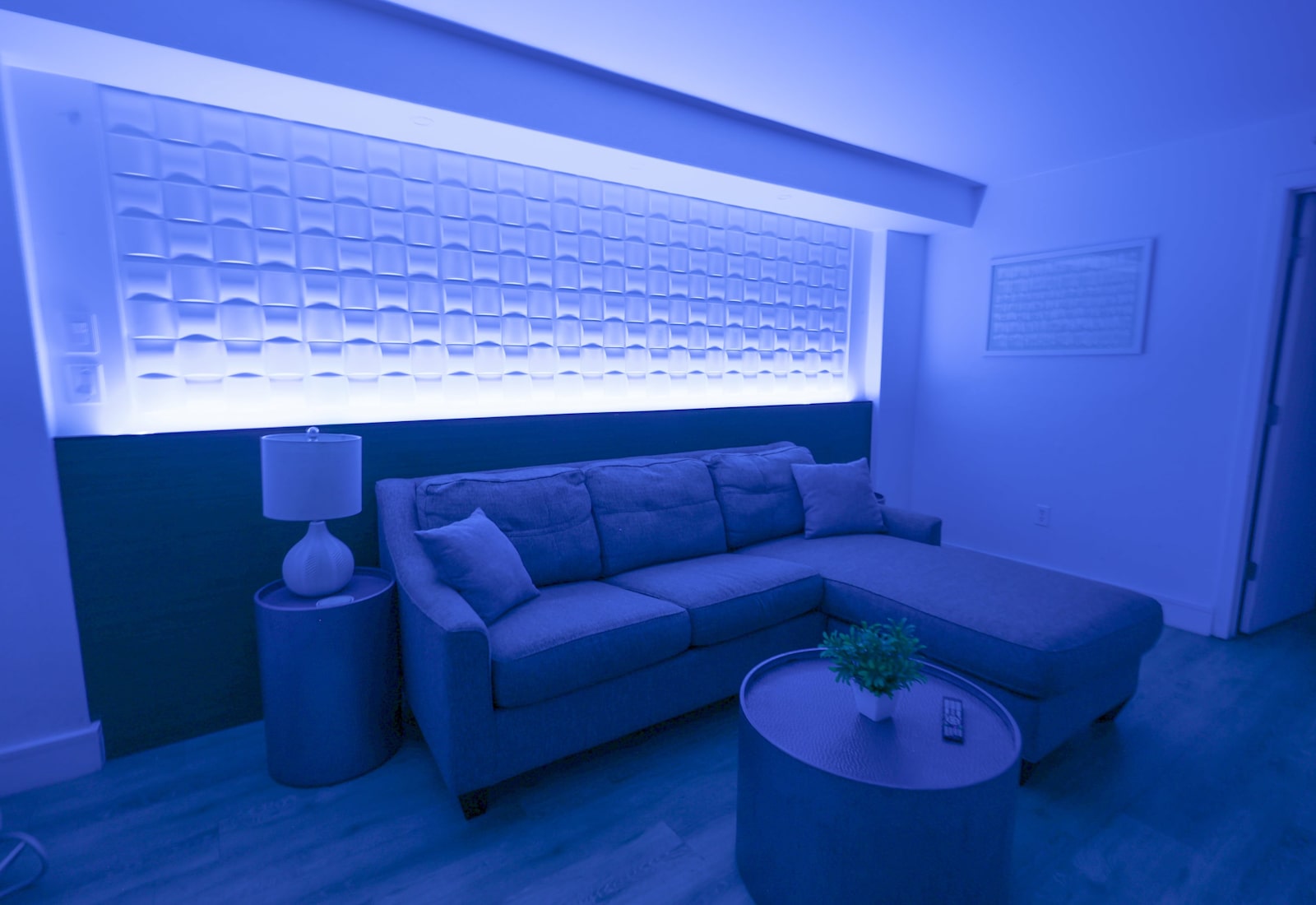Ambient LED lighting, sectional sofa, and a textured feature wall—perfect for relaxing in a stylish, cozy atmosphere.