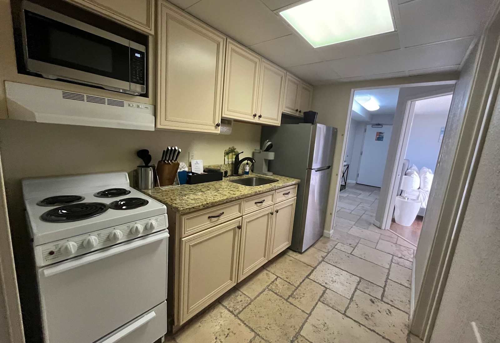 Convenient kitchen area featuring a full-size fridge, stove, microwave, sink, and easy access to the living space.