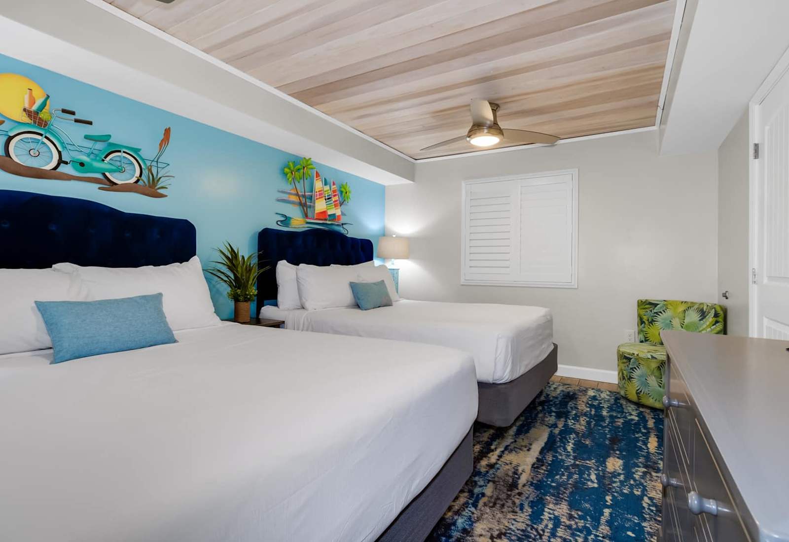 Rest easy in this vibrant and spacious bedroom featuring two plush beds, cozy coastal decor, and artistic wall accents that capture the essence of a beach getaway. With comfort and style in every detail, it’s the perfect space for a peaceful retreat.