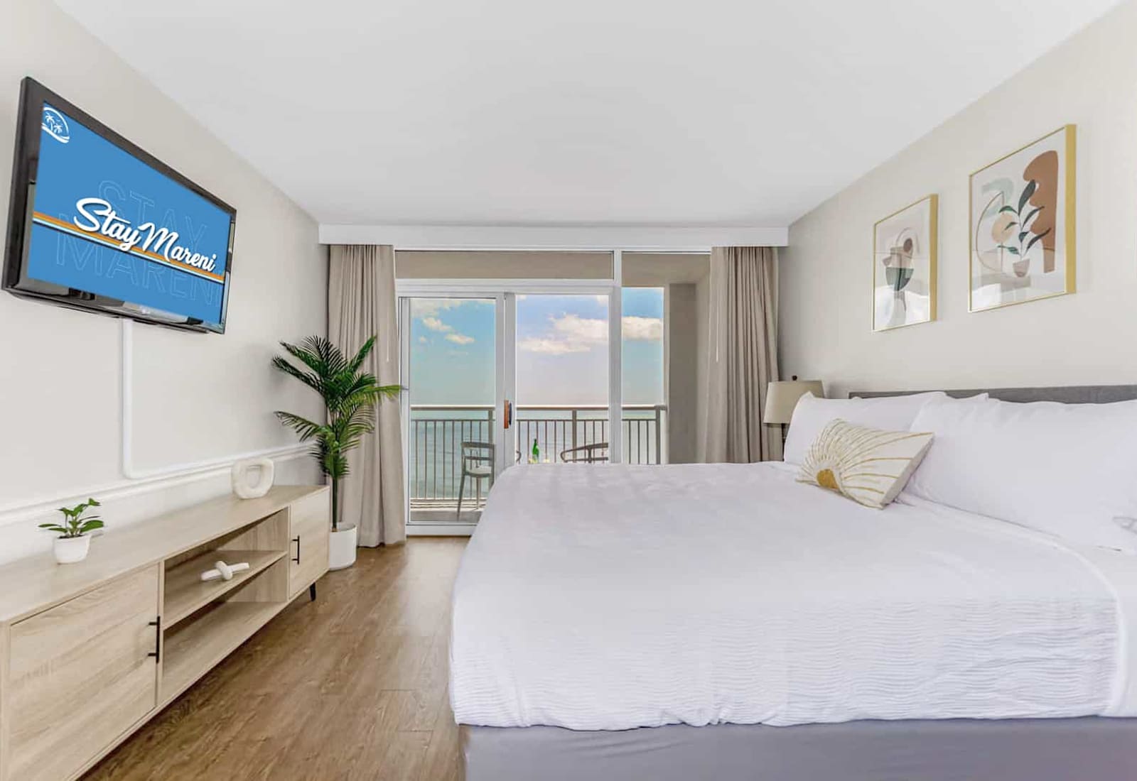Wake up to breathtaking ocean views in this modern, serene bedroom featuring a plush king-size bed, stylish decor, and direct access to a private balcony. Relax in comfort with a flat-screen TV and soothing natural tones of the waves from the ocean.
