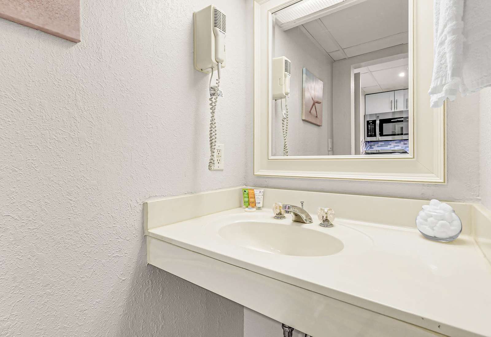 Freshen up in this bright, well-kept vanity area featuring a spacious countertop, large mirror, and complimentary toiletries—conveniently located just steps from the bedroom and kitchenette.