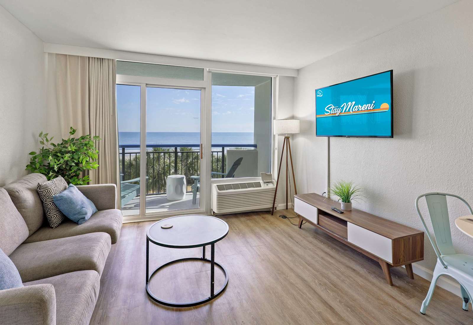 Open-concept coastal retreat featuring stylish décor, a comfortable lounge area, and floor-to-ceiling windows with relaxing ocean views just beyond.