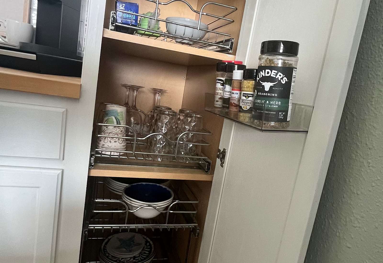 Well organized pantry cabinet fully stocked with glassware, dishes, and kitchen essentials