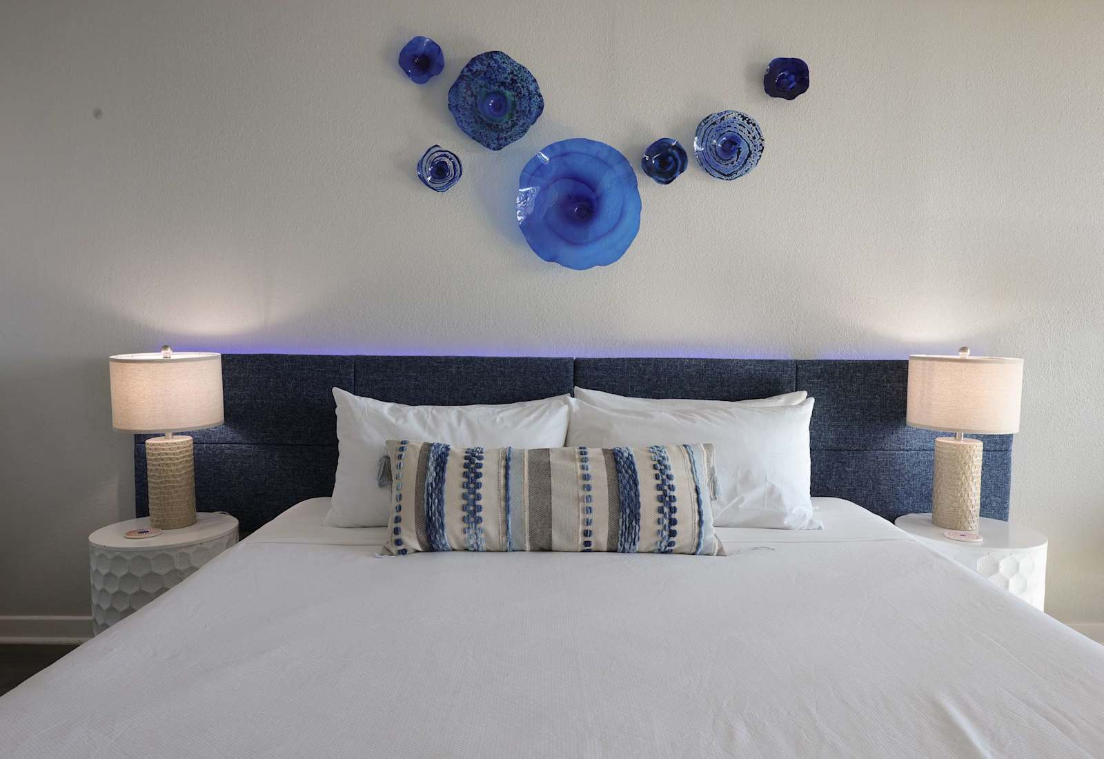 Wake up to beautiful beach views from this airy coastal retreat, featuring a plush bed, soothing blue décor, and a cozy seating nook by the balcony.
