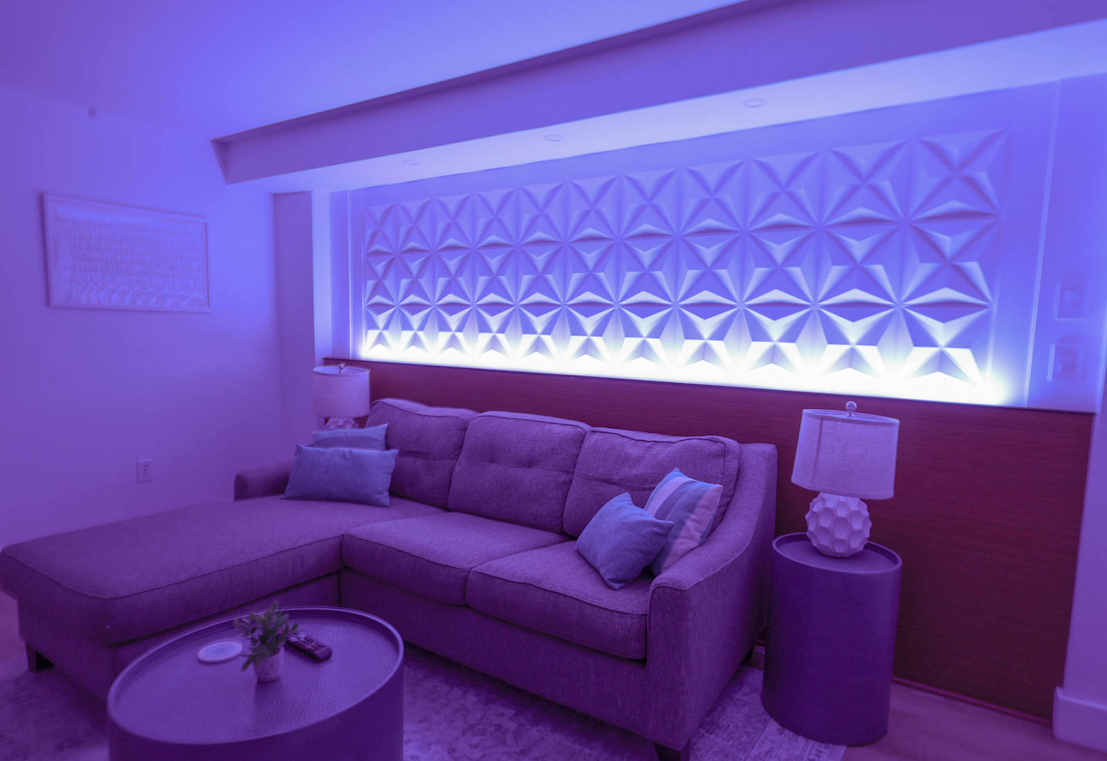 Ambient LED lighting, a sleek sectional sofa, and a textured feature wall—perfect for relaxing in a stylish, cozy atmosphere.