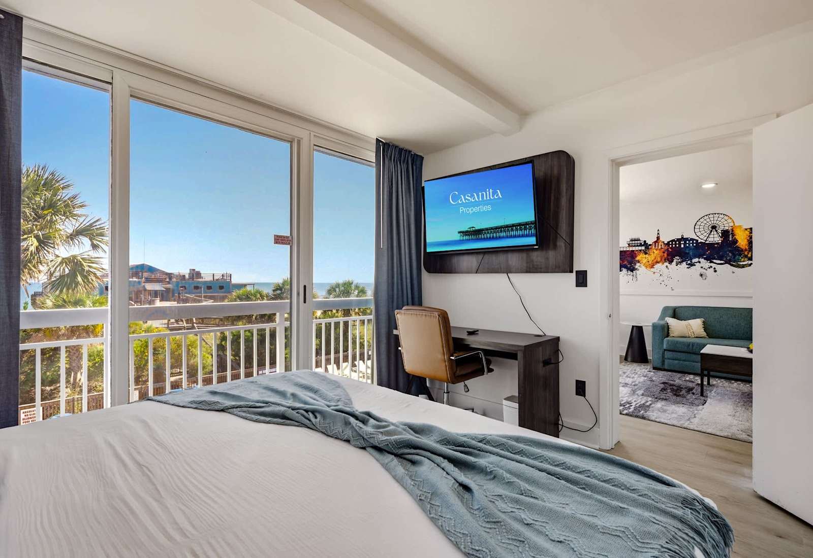 Rest easy in this bright, airy bedroom featuring a serene coastal accent wall and direct balcony access!