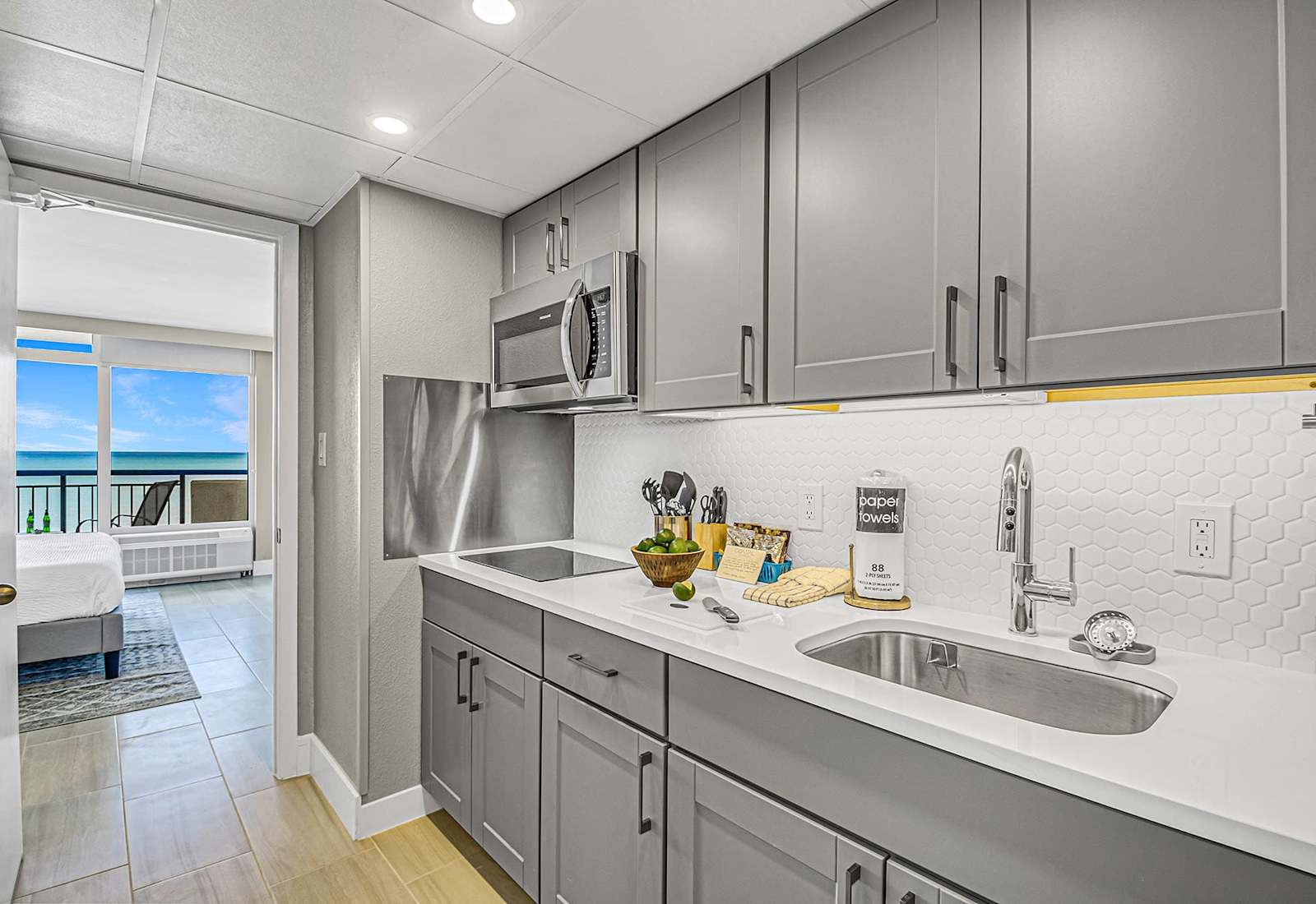 Modern kitchen with sleek cabinetry and a stylish blue-tile backsplash, fully equipped for your culinary needs. Just steps from the bedroom, this space offers convenience and functionality, allowing you to enjoy meals with a stunning ocean view.