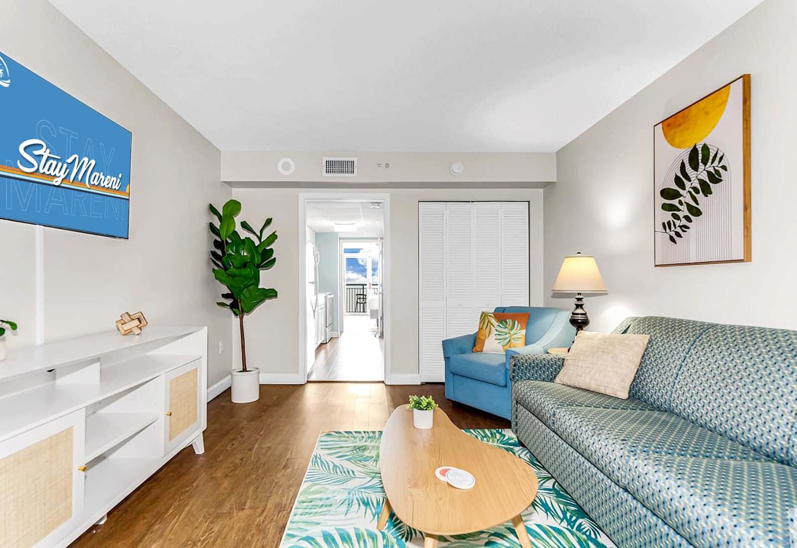 Unwind in the cozy living space featuring modern décor, lush greenery, and vibrant art. Perfect for relaxing after a day of exploring or enjoying your favorite shows.