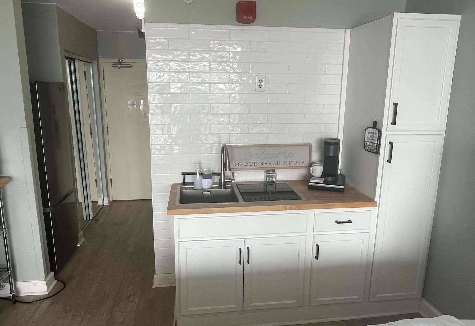 Modern kitchenette equipped with a coffee maker, sink, cooktop, and generous pantry storage