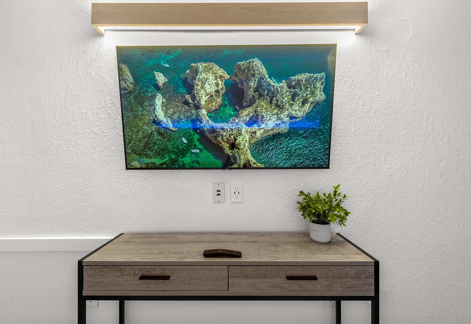 Unwind after a day at the beach with your favorite shows on this sleek flat-screen TV, perfectly set above a modern wood desk—ideal for both entertainment and a touch of productivity during your coastal getaway.
