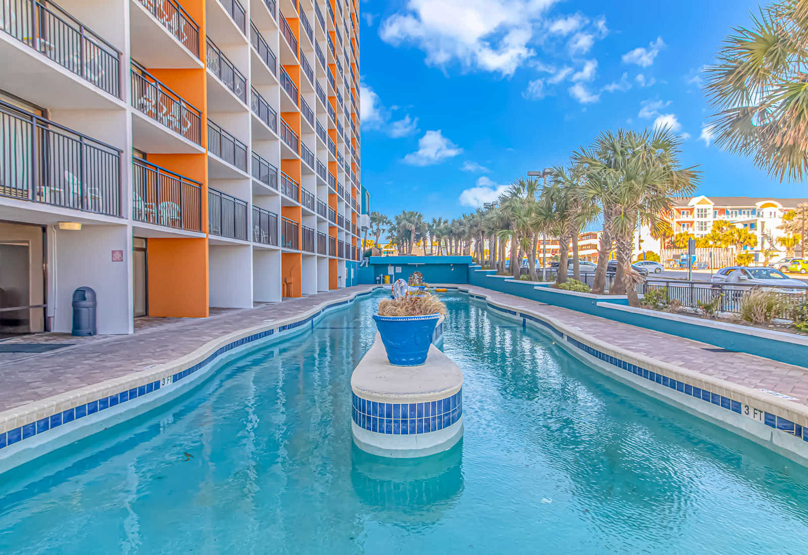 Outdoor resort pool with palm trees, lounge areas, and bright Myrtle Beach scenery for a refreshing coastal escape.