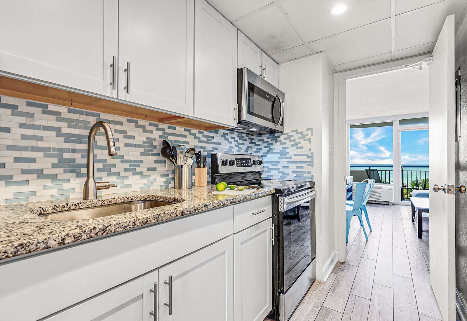 Modern kitchen with sleek cabinetry and a stylish blue-tile backsplash, fully equipped for your culinary needs. Just steps from the bedroom, this space offers convenience and functionality, allowing you to enjoy meals with a stunning ocean view.