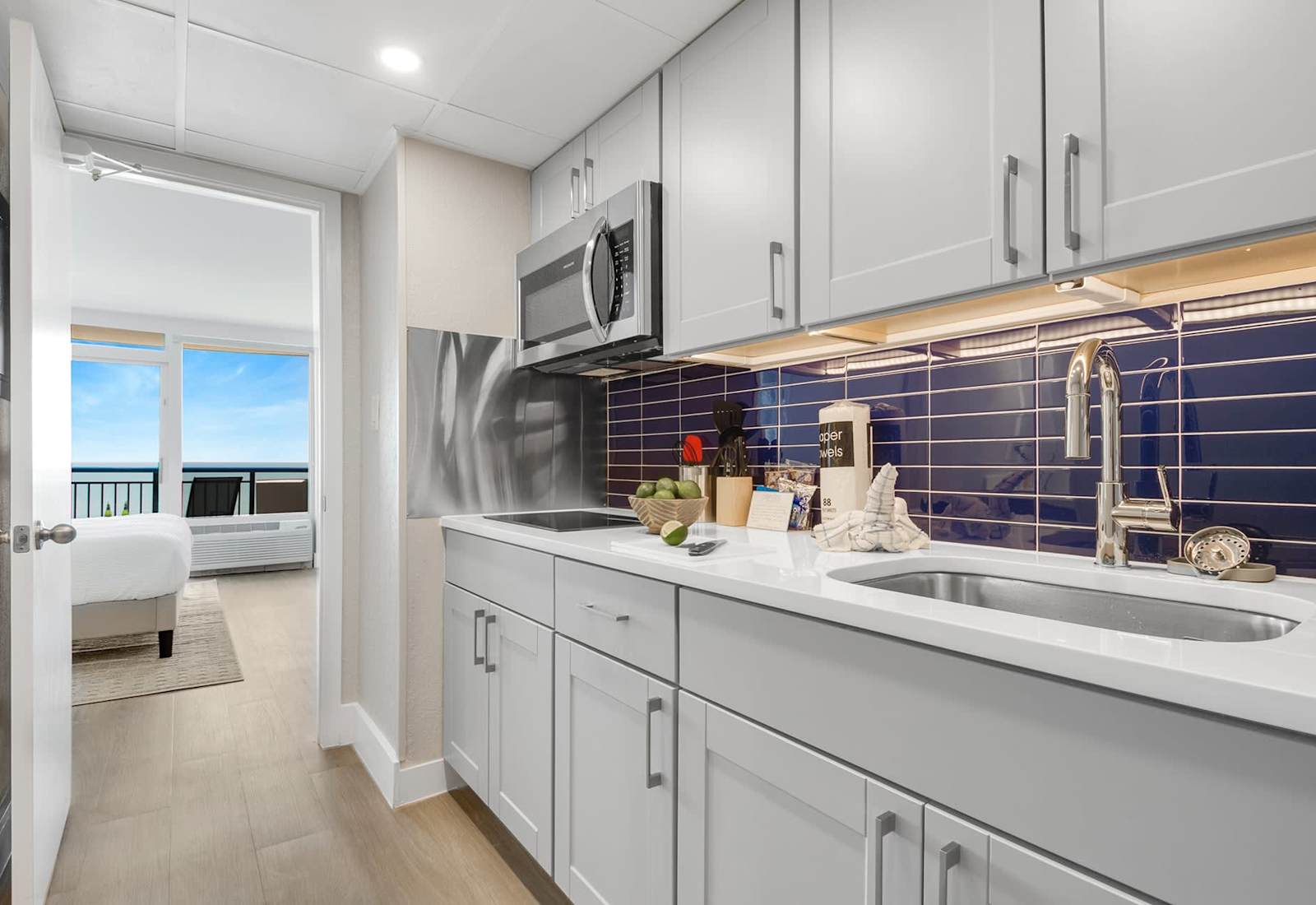 Modern kitchen with sleek cabinetry and a stylish blue-tile backsplash, fully equipped for your culinary needs. Just steps from the bedroom, this space offers convenience and functionality, allowing you to enjoy meals with a stunning ocean view.