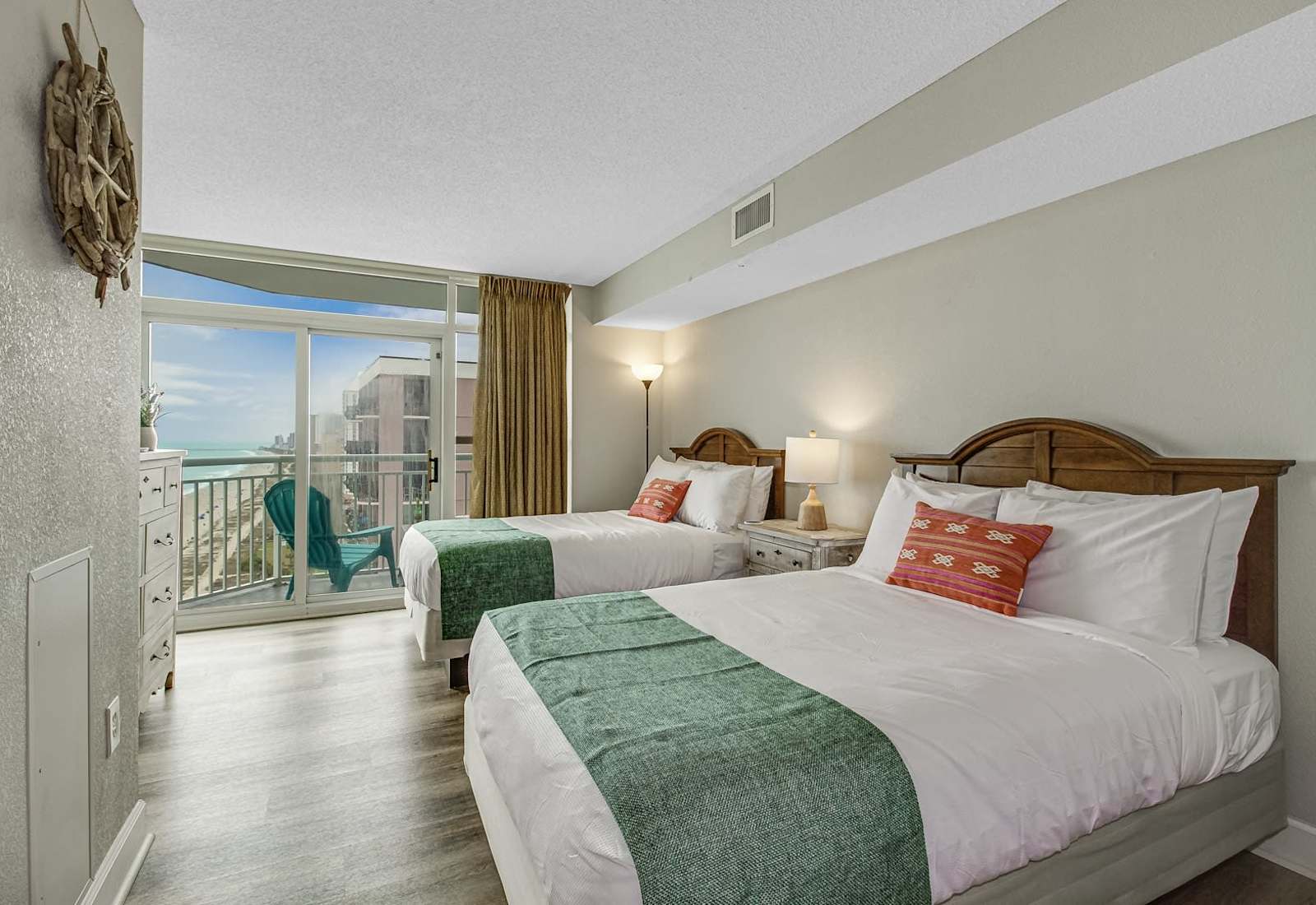 Welcoming bedroom setup with two beds, warm wood headboards, fresh white bedding, and easy balcony access for a relaxed beach stay.