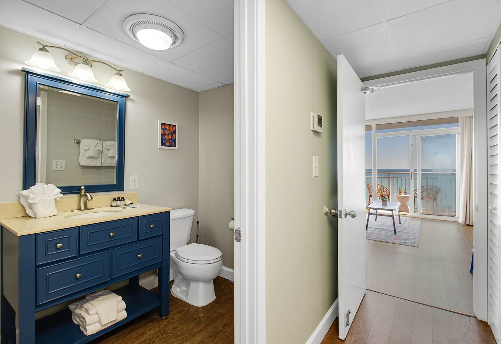 Step into this inviting space where elegance meets comfort. The bathroom features contemporary fixtures, while just beyond, the open doorway reveals a light-filled living area with stunning ocean views.