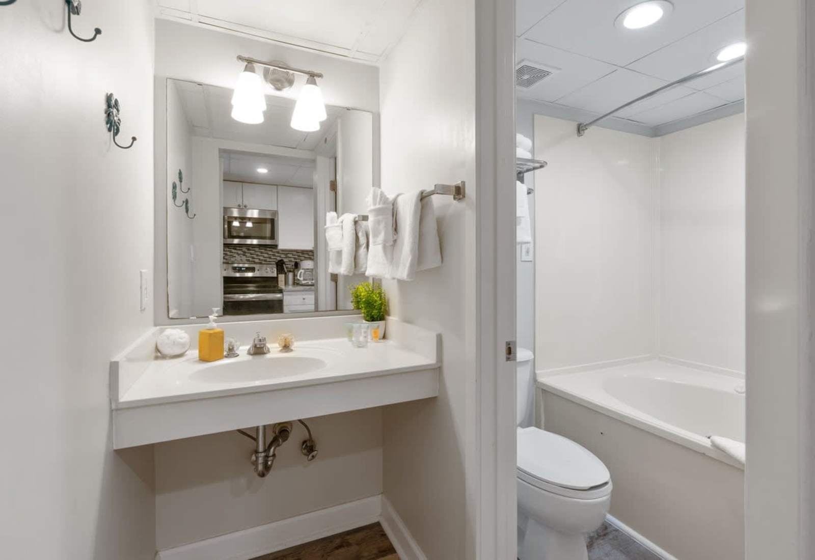 Bright and spotless bathroom featuring a spacious vanity, fresh towels, and a relaxing tub—perfect for refreshing after a beach day or unwinding before a cozy night in.