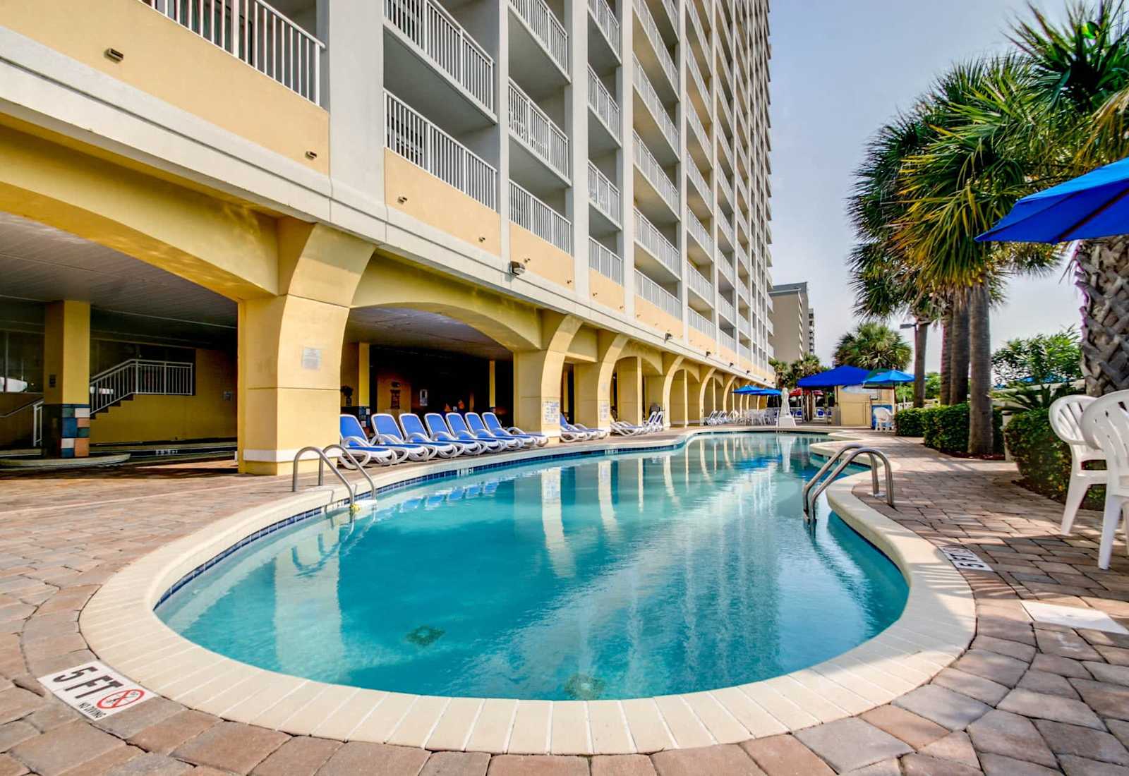 Take a refreshing dip in this inviting pool, perfectly situated under the building's shade for a cool retreat. With comfortable lounge chairs and a relaxed vibe, it’s the perfect spot to unwind after a fun day at the beach. 