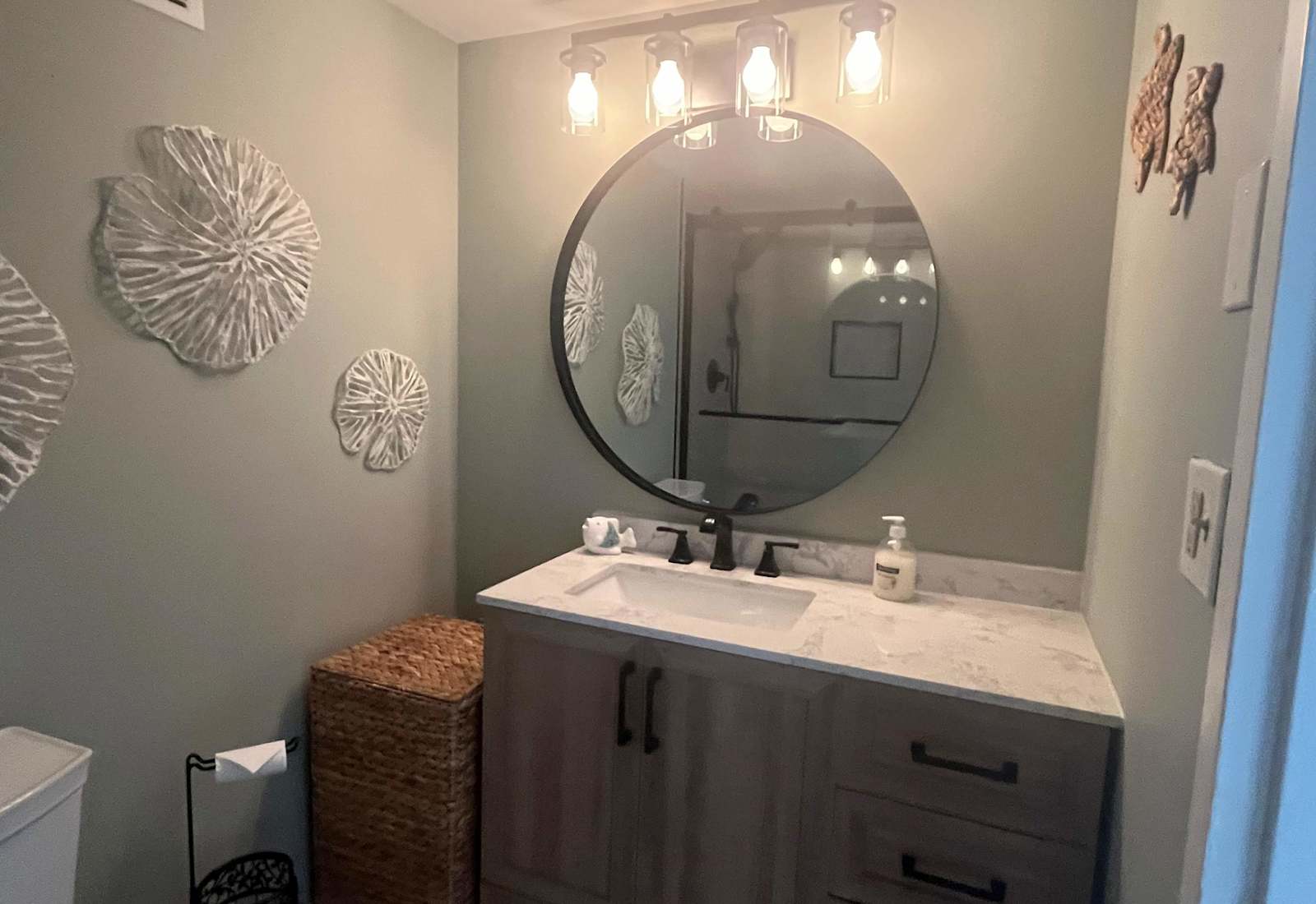 Stylish bathroom vanity with a large round mirror, stone countertop, and modern lighting