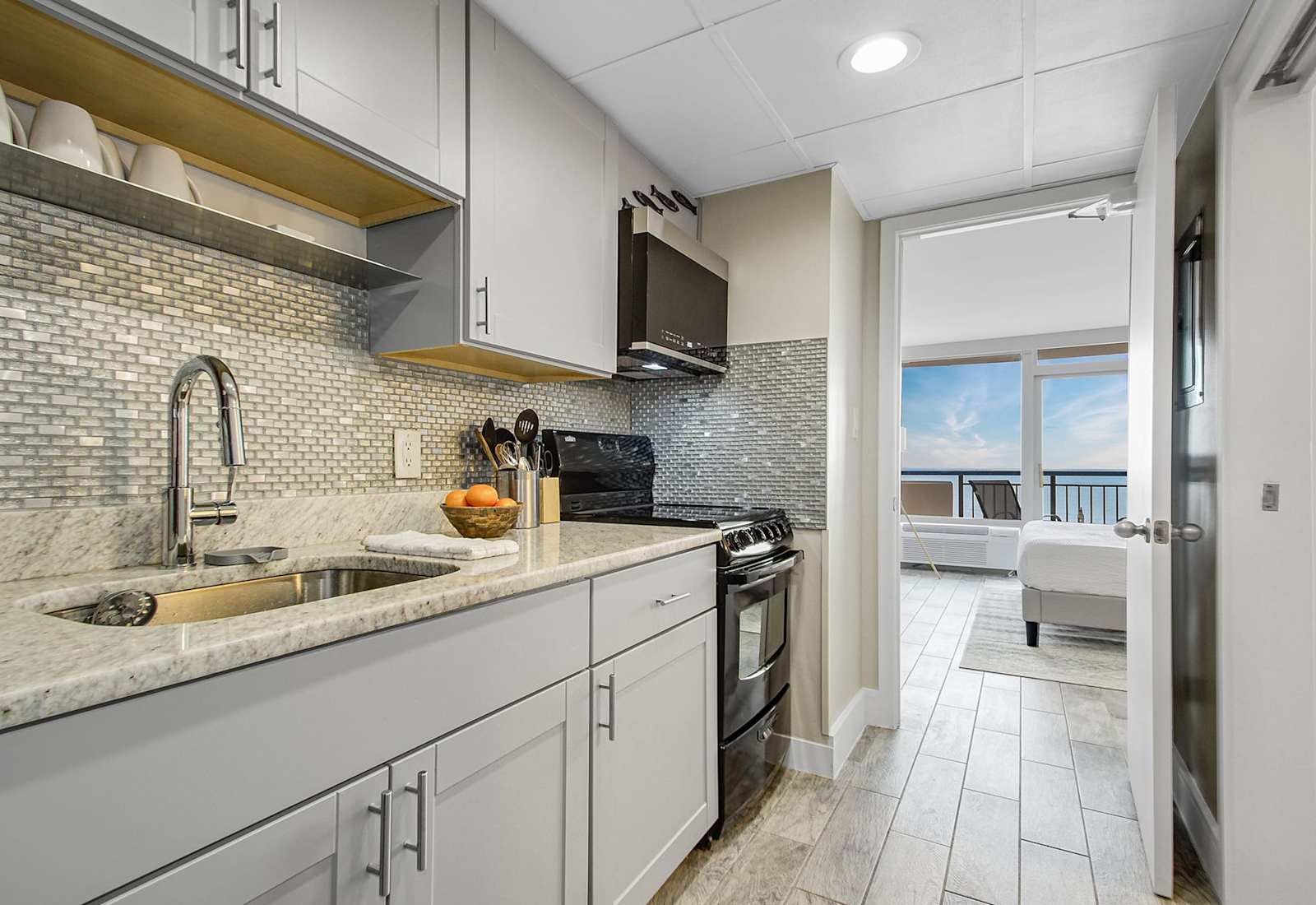 Modern kitchen with sleek cabinetry and a stylish blue-tile backsplash, fully equipped for your culinary needs. Just steps from the bedroom, this space offers convenience and functionality, allowing you to enjoy meals with a stunning ocean view.