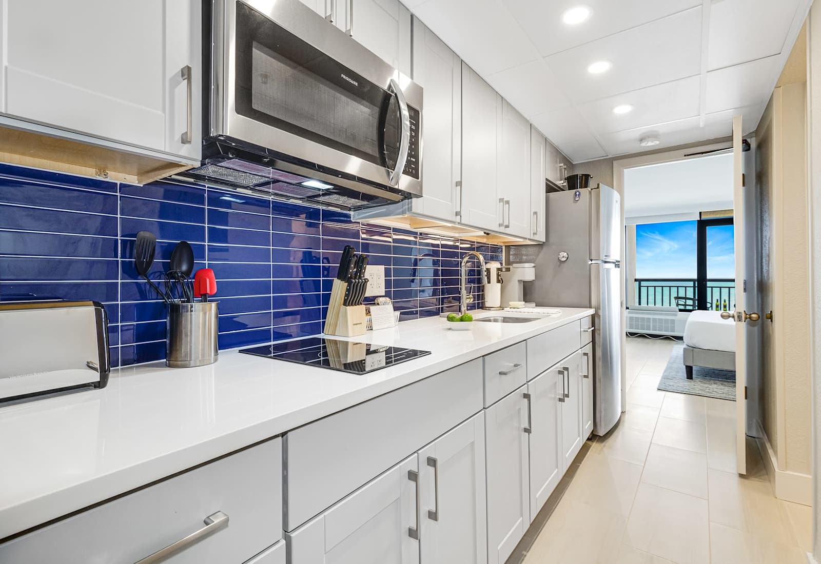 Modern kitchen with stainless steel appliances, quartz countertops, and ocean views. 

