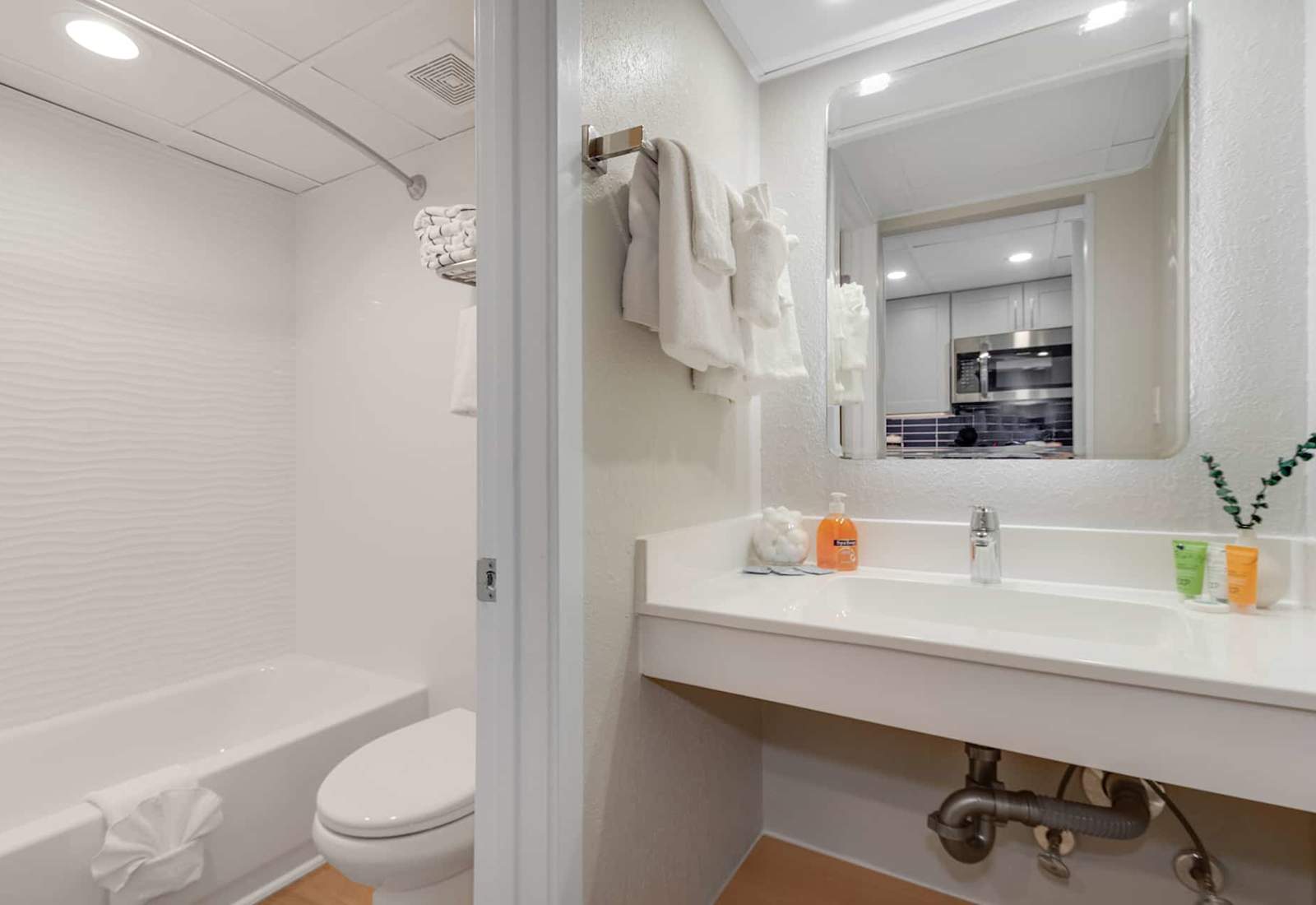 Bright and clean bathroom with modern touches. Relax in the tub or refresh at the spacious vanity, complete with soft towels and quality toiletries. Every detail is thoughtfully arranged to offer a soothing and comfortable experience.