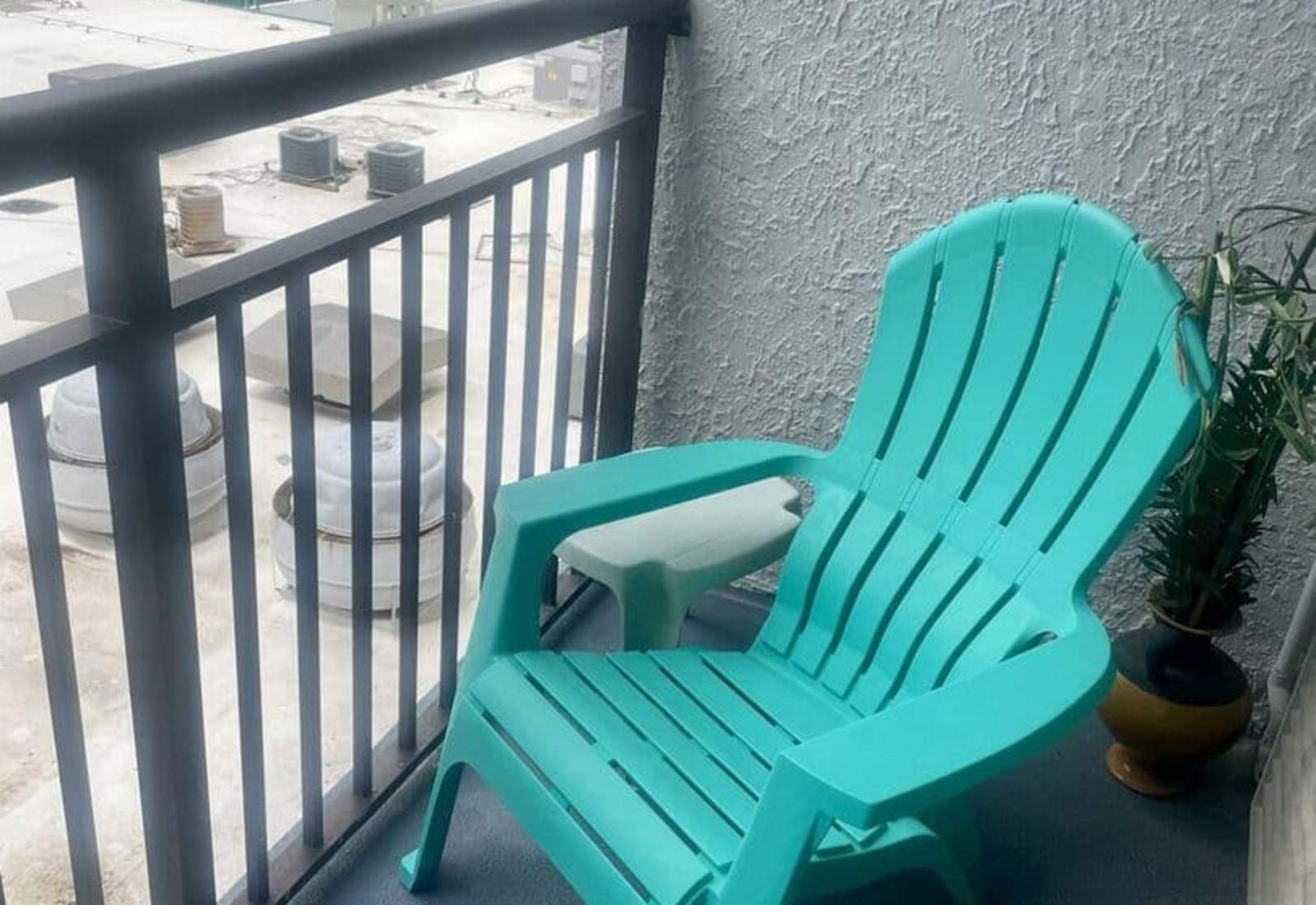 Private balcony seating featuring a vibrant turquoise Adirondack chair and small matching side table.