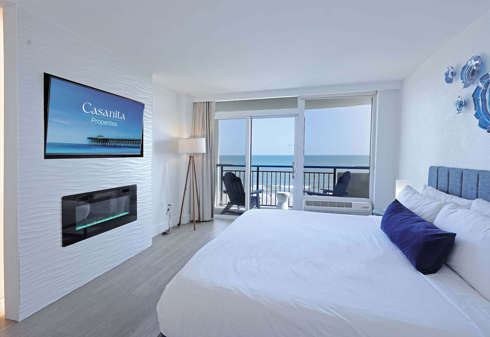 Wake up to breathtaking ocean views from your cozy bedroom retreat, featuring a plush bed, flat-screen TV, and private balcony access for the perfect blend of comfort and coastal charm.