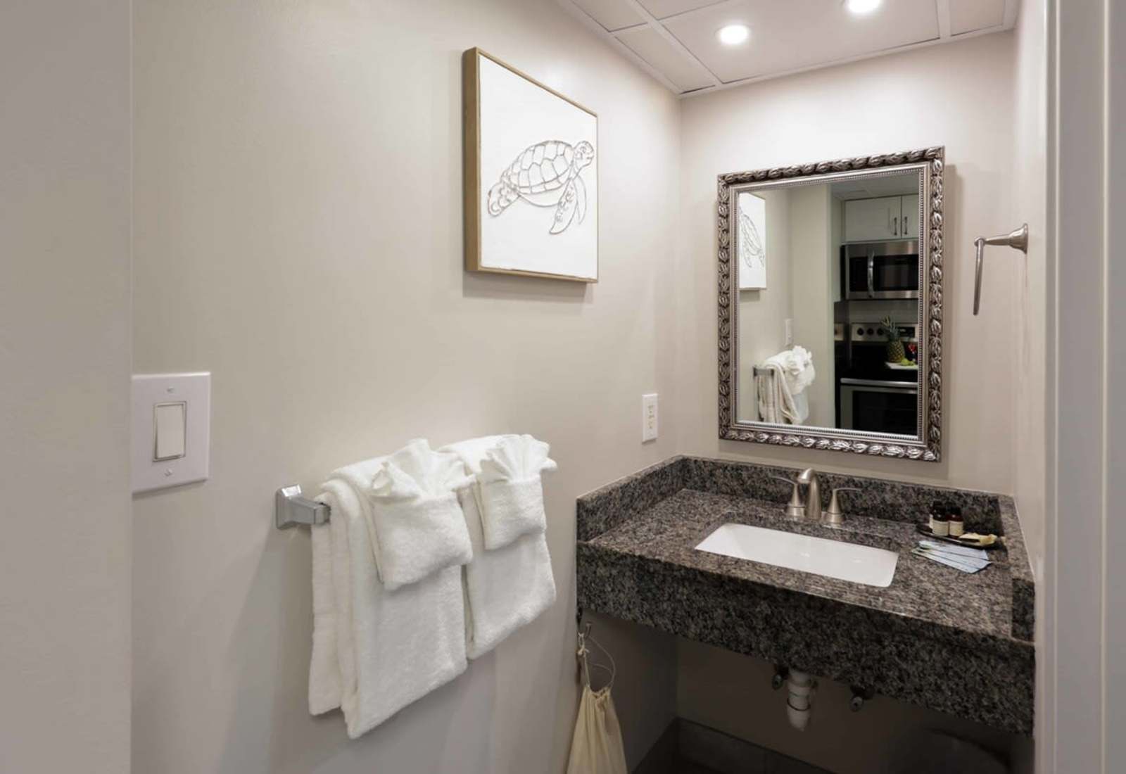 Freshen up in style! 🐢 This sleek vanity space features granite countertops, spa-inspired towels, and coastal charm—because even your mirror selfies deserve a 5-star backdrop.