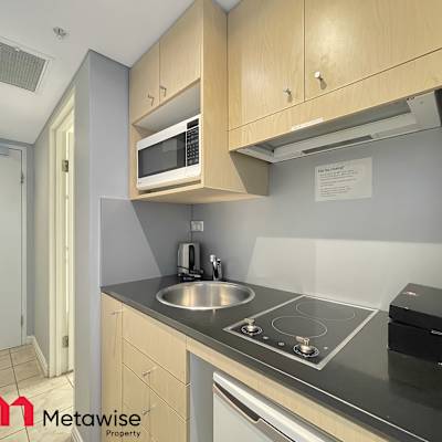 Compact kitchen with cooktop, sink, microwave, and essential appliances.