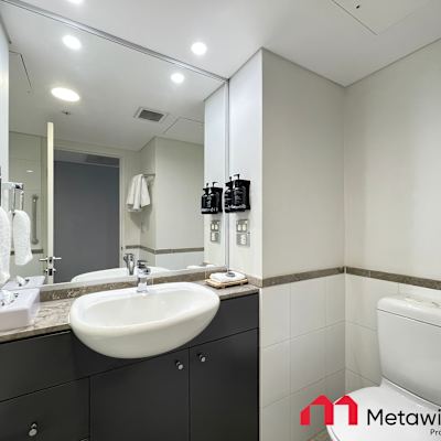 Bathroom with vanity, mirror, toilet, and shower area.