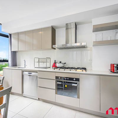 Modern kitchen with stone benchtops, cooktop, oven, rangehood, and large windows with city views.