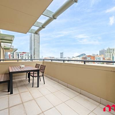 Spacious balcony with outdoor table and sweeping city views.