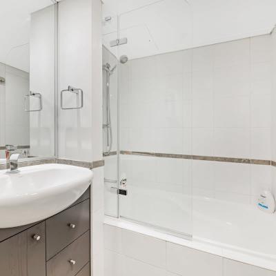Bathroom with vanity, mirror, bathtub with shower, and toilet.