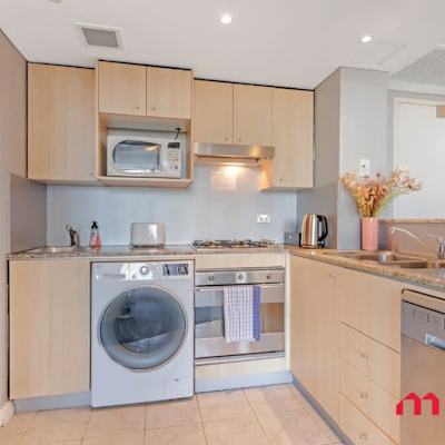 Fully equipped kitchen with cooktop, oven, microwave, washing machine, and ample cabinetry.