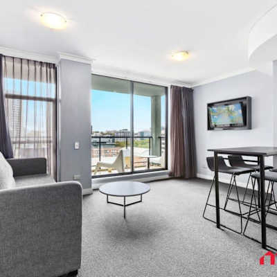 Living area with sofa seating, dining space, wall-mounted TV, and city views. (Includes sofa bed for additional guests.)