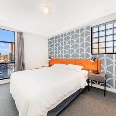 BedroomBedroom featuring a king-size bed, stylish feature wall, bedside tables, and city views.