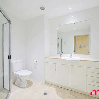 Modern bathroom with glass-enclosed shower, toilet, vanity with storage, and large mirror.
