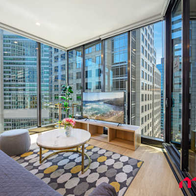 Living area with floor-to-ceiling windows, city views, sofa (sofa bed), and balcony access.