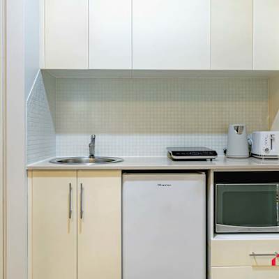 Compact kitchenette with sink, microwave, bar fridge, cabinetry, and tea/coffee facilities.