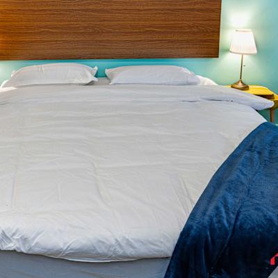 Close-up of the queen-sized bed with bedside lighting and wooden headboard.